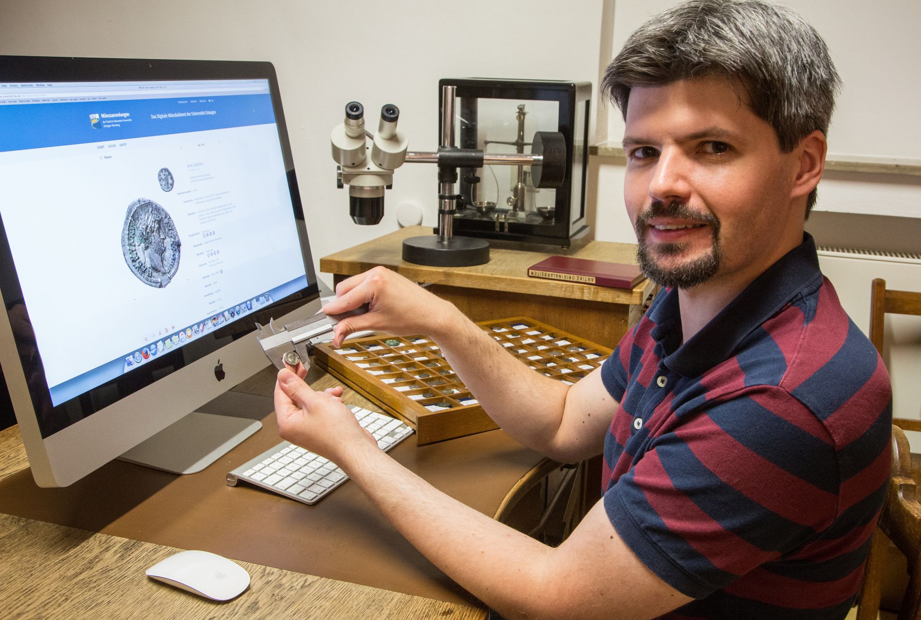 Forscher mit Münze vor Bildschirm
