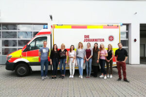 Eine Gruppe von Menschen steht vor einem Rettungswagen.