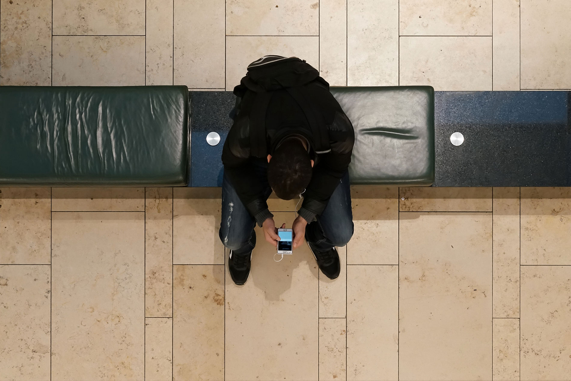 Junger Mann schaut auf sein Smartphone.