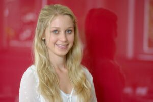 Eine Frau mit langen blonden Haaren vor einem roten Hintergrund