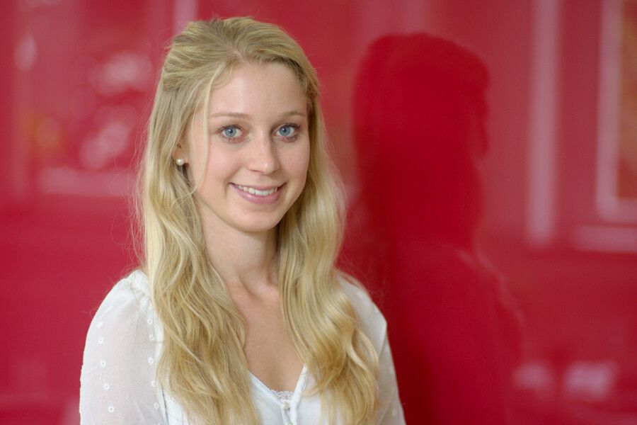 Eine Frau mit langen blonden Haaren vor einem roten Hintergrund