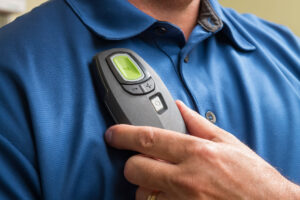 Mann hält Fernbedienung des Zungenschrittmachers.