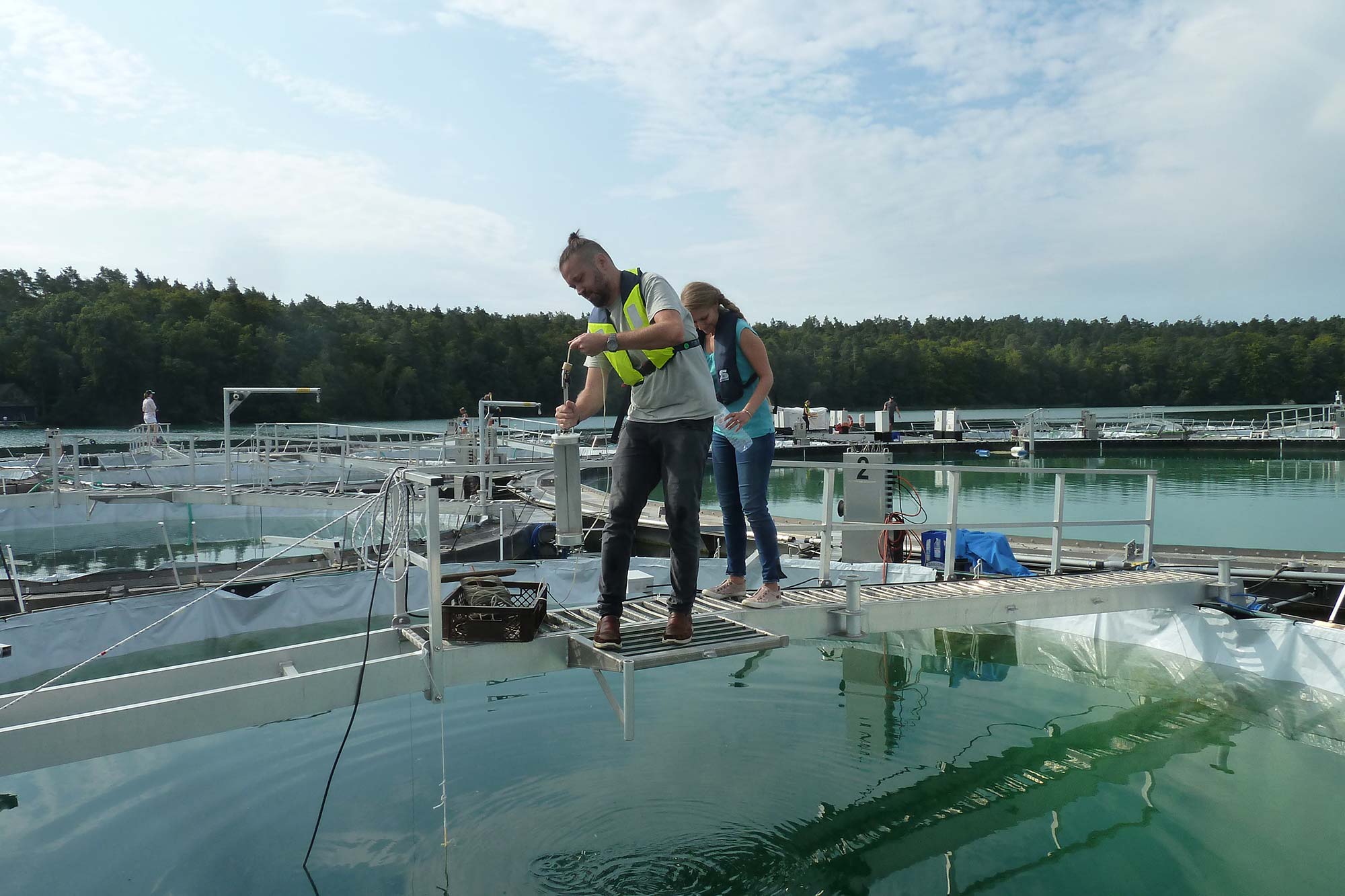 Dr. Alexander Frank und eine Kollegin entnehmen eine Wasserprobe.