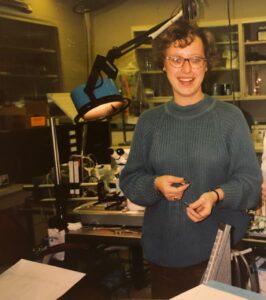 Eine junge Frau in einem Labor, die in die Kamera blickt.