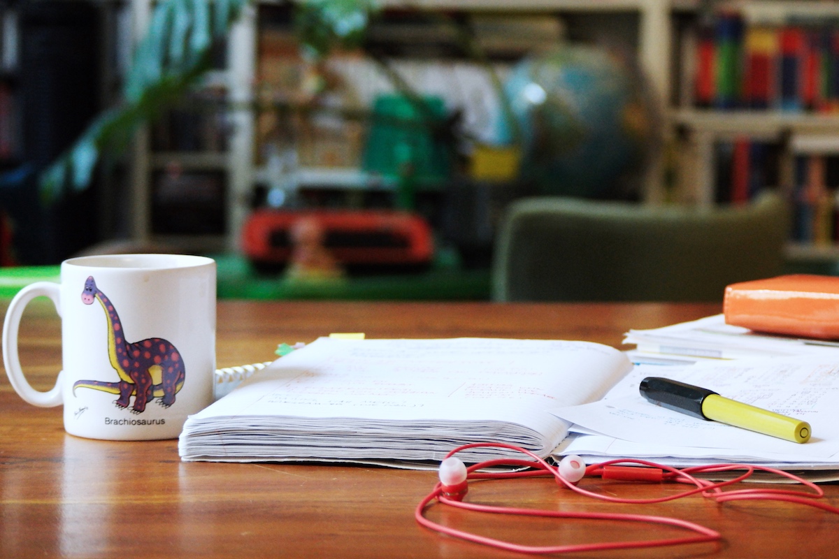 Dino-Tasse, Schreibzeug auf Schreibtisch, Kopfhörer