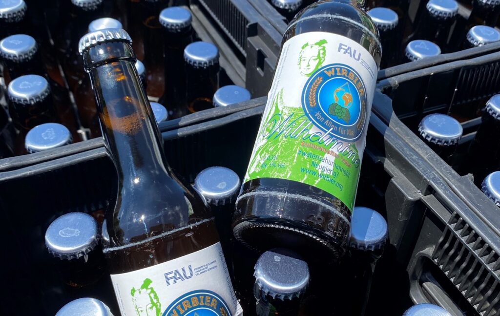 Zwei Bierflaschen liegen auf mehreren Bierkästen.
