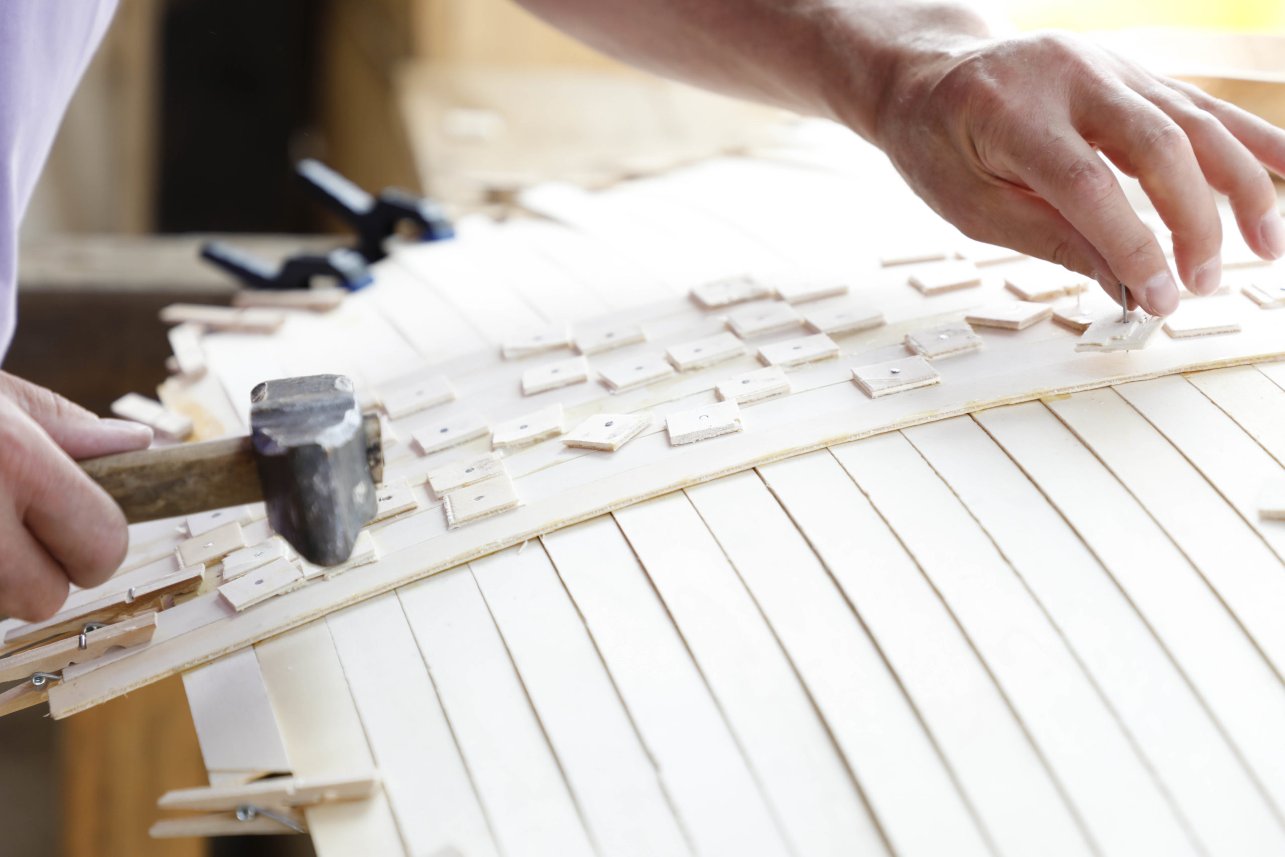 Holzleisten werden für ein Schild zusammengeleimt.
