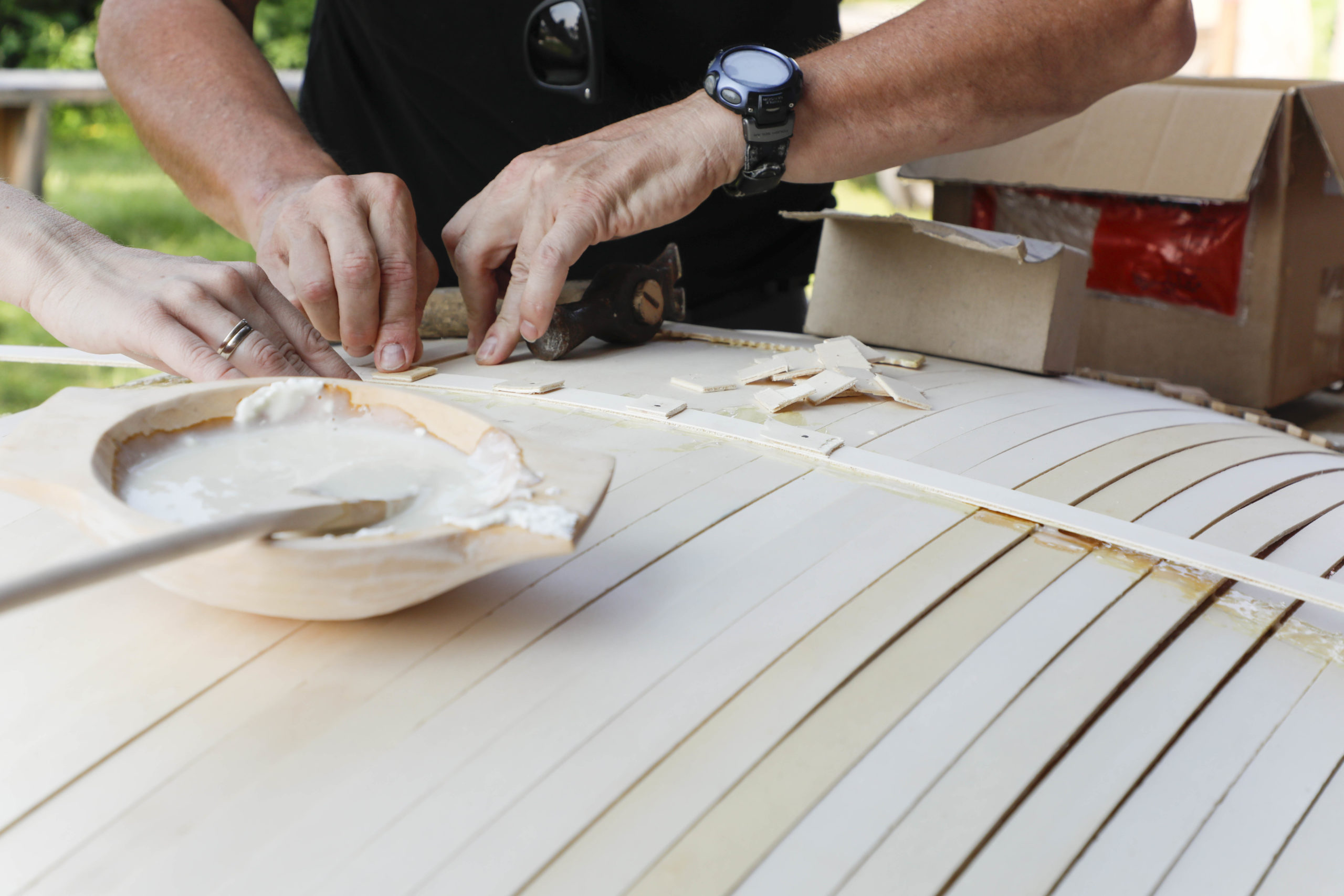 Holzleisten werden für ein Schild zusammengeleimt.