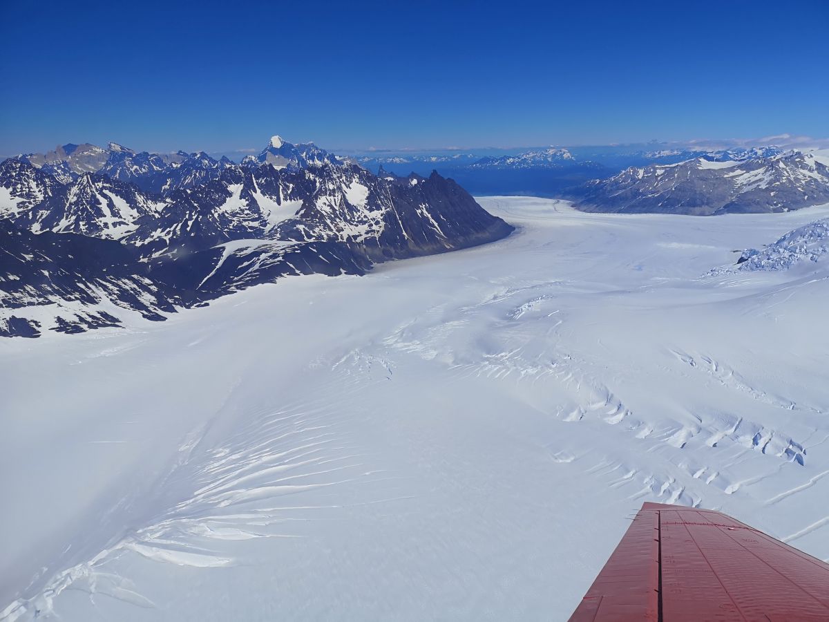 Panoramafoto aus dem Flugzeug. Am unteren Rand des Fotos sieht man einen Flugzeugflügel.