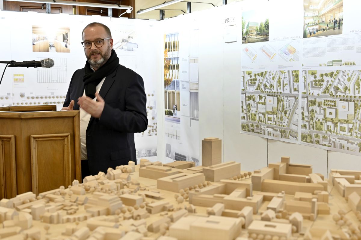 Rede am Rednerpult vor Modell des Hörsaalzentrums