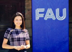 Junge Frau vor FAU-Logo