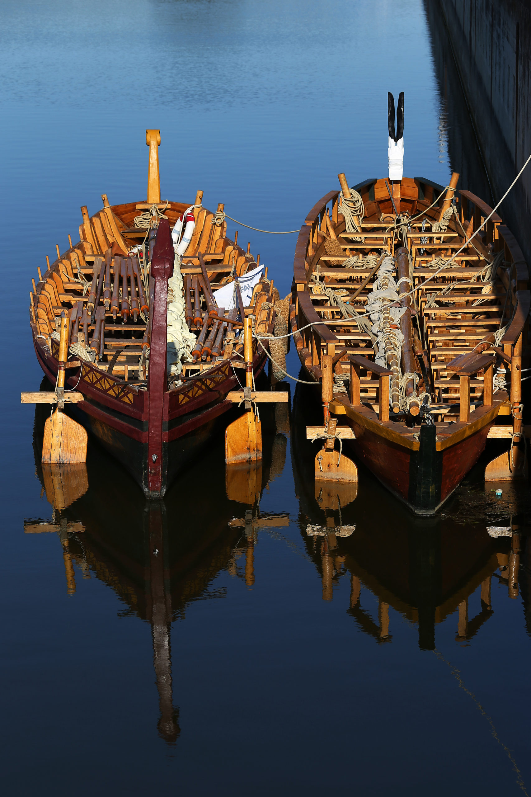 Im Hafenbecken liegen zwei Römerboote im Wasser nebeneinander.