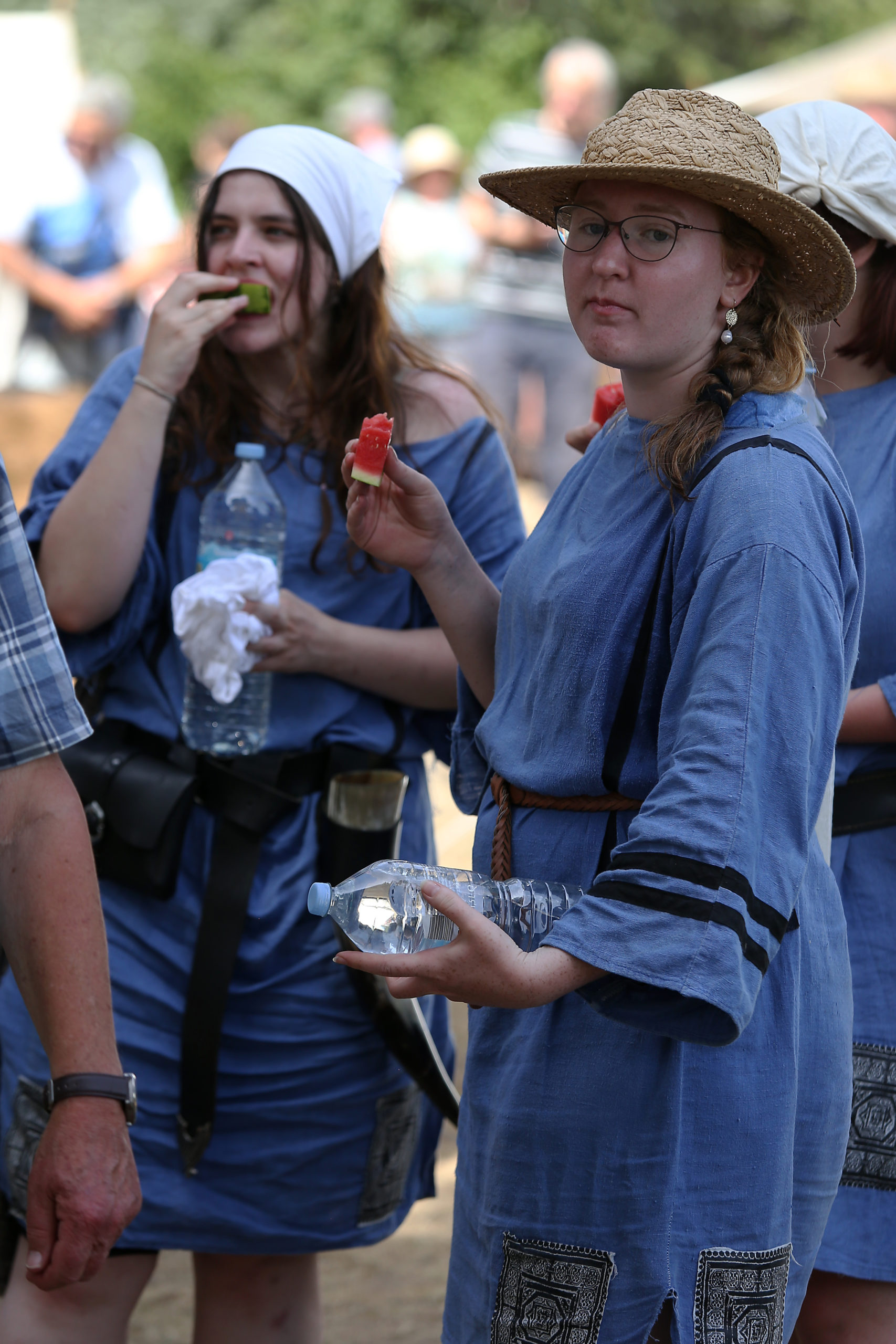 Drei Frauen in blauen Gewändern machen eine Pause, trinken Wasser und essen Wassermelone.