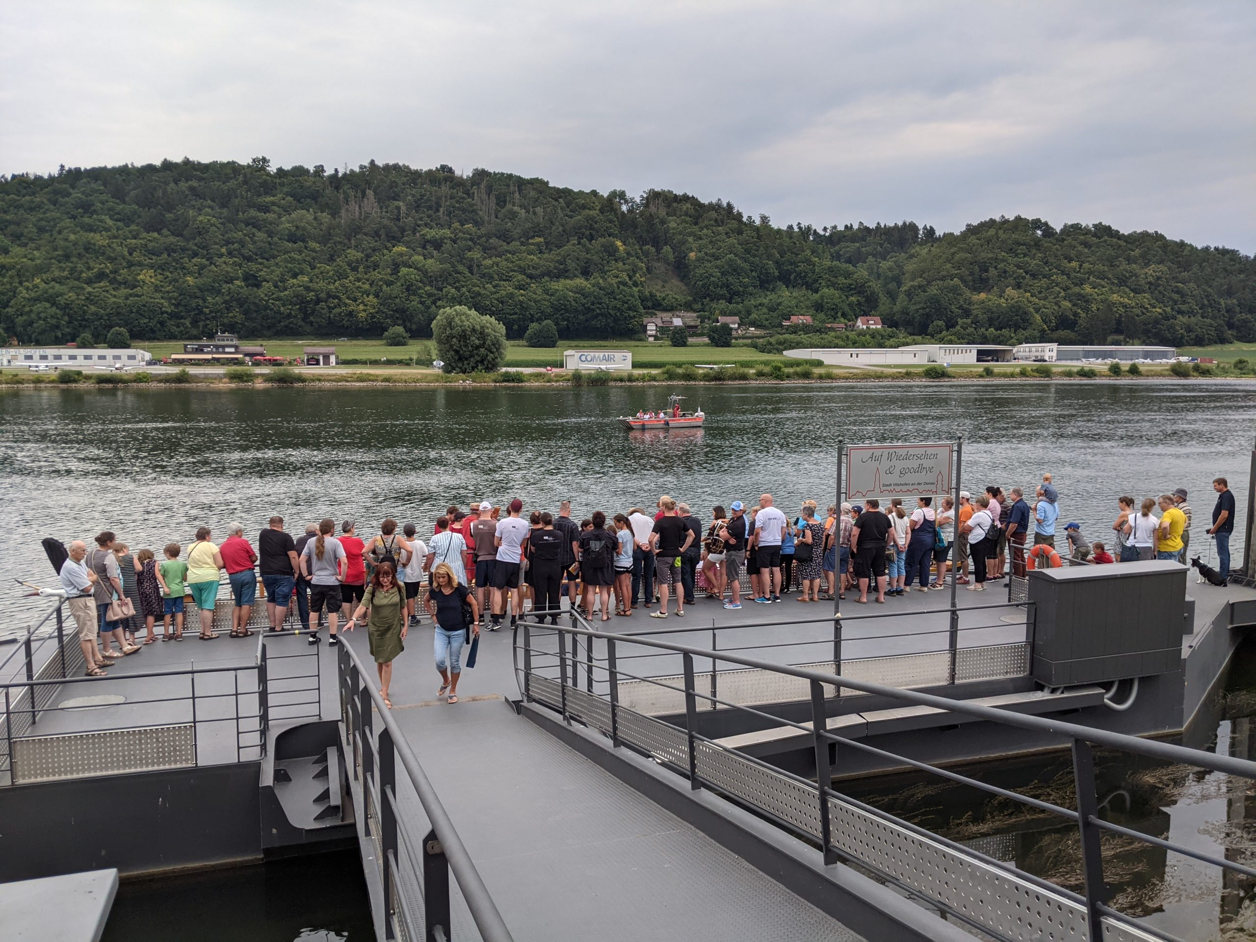 Touristen beobachten auf einem Steg die Ankunft eines Römerboot.