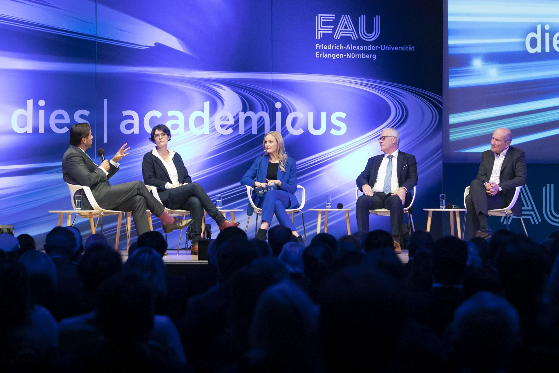 Diskussionsrunde auf einer Bühne mit fünf Personen.