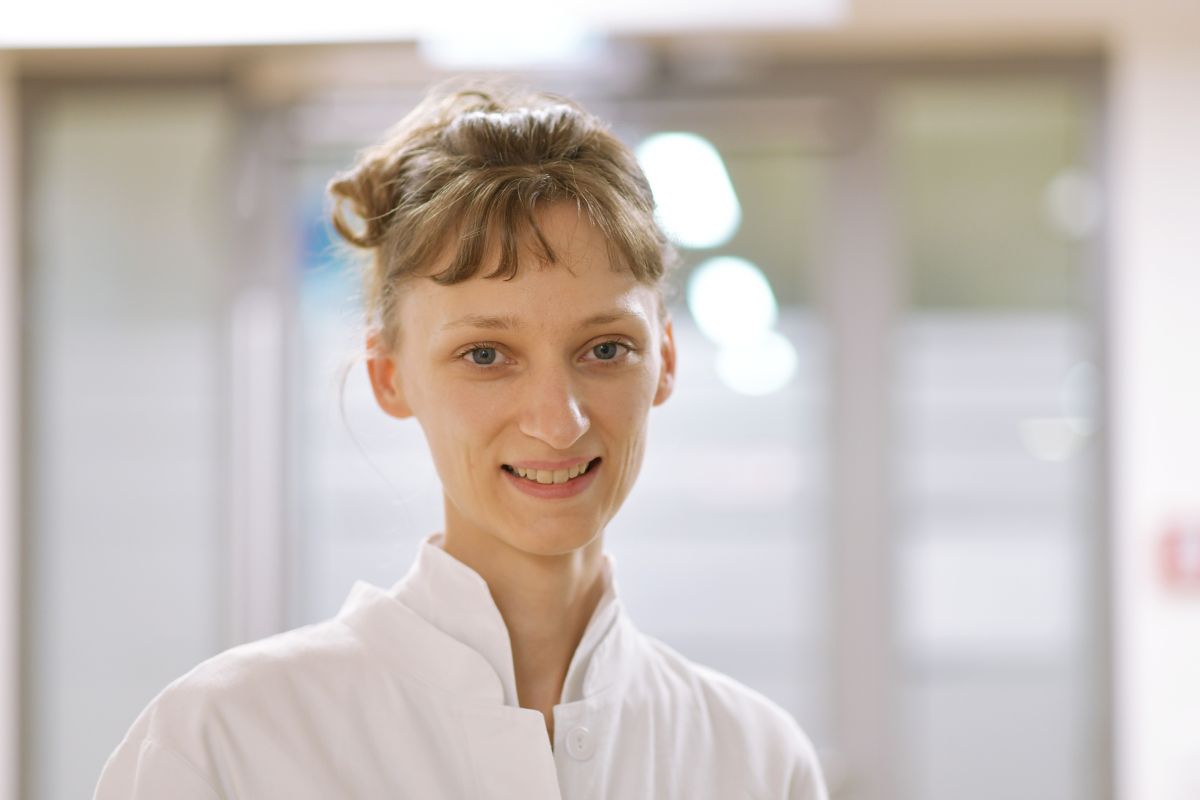 Porträt einer Frau in weißem Kittel und blonden Haaren.