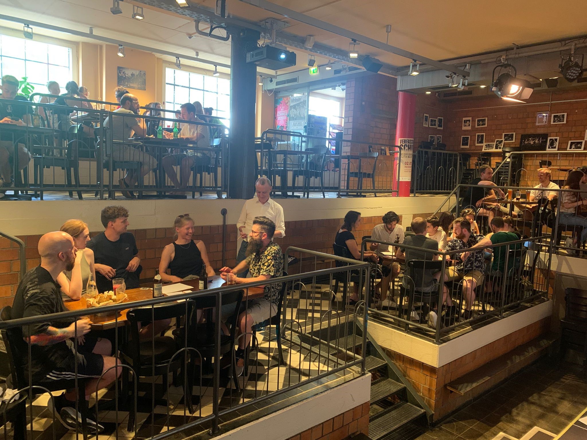 FAU-Kneipenquiz in der Kellerbühne im E-Werk: Bühne mit Moderation, Tische mit Teilnehmenden