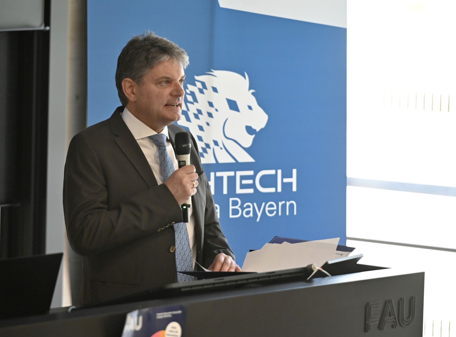 Präsident der Friedrich-Alexander-Universität Erlangen-Nürnberg Joachim Hornegger mit Mikro am Podium