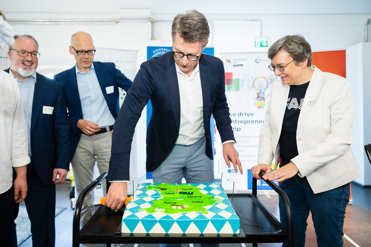Der Wissenschaftsminister Markus Blume schneidet den Kuchen an.