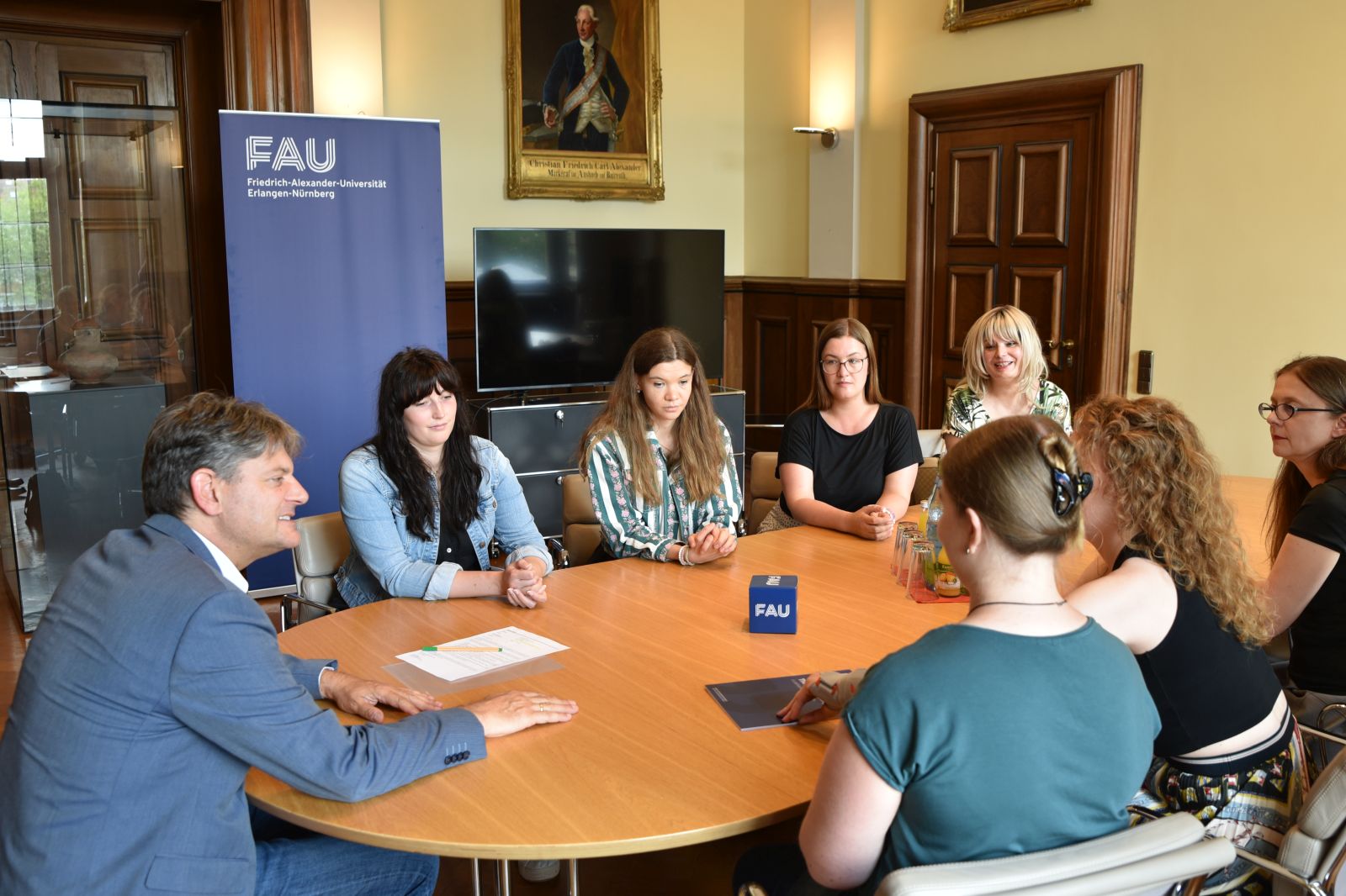 Universitätsleitung sitzt mit Studierenden und Diversitybeauftragten an Tisch und bespricht Wünsche aus der Kampagne Wünschewand.