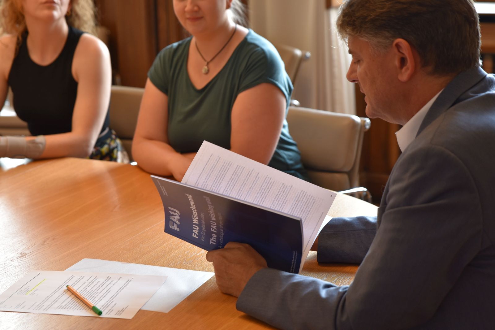 Universitätsleitung sitzt mit Studierenden und Diversitybeauftragten an Tisch und bespricht Wünsche aus der Kampagne Wünschewand.