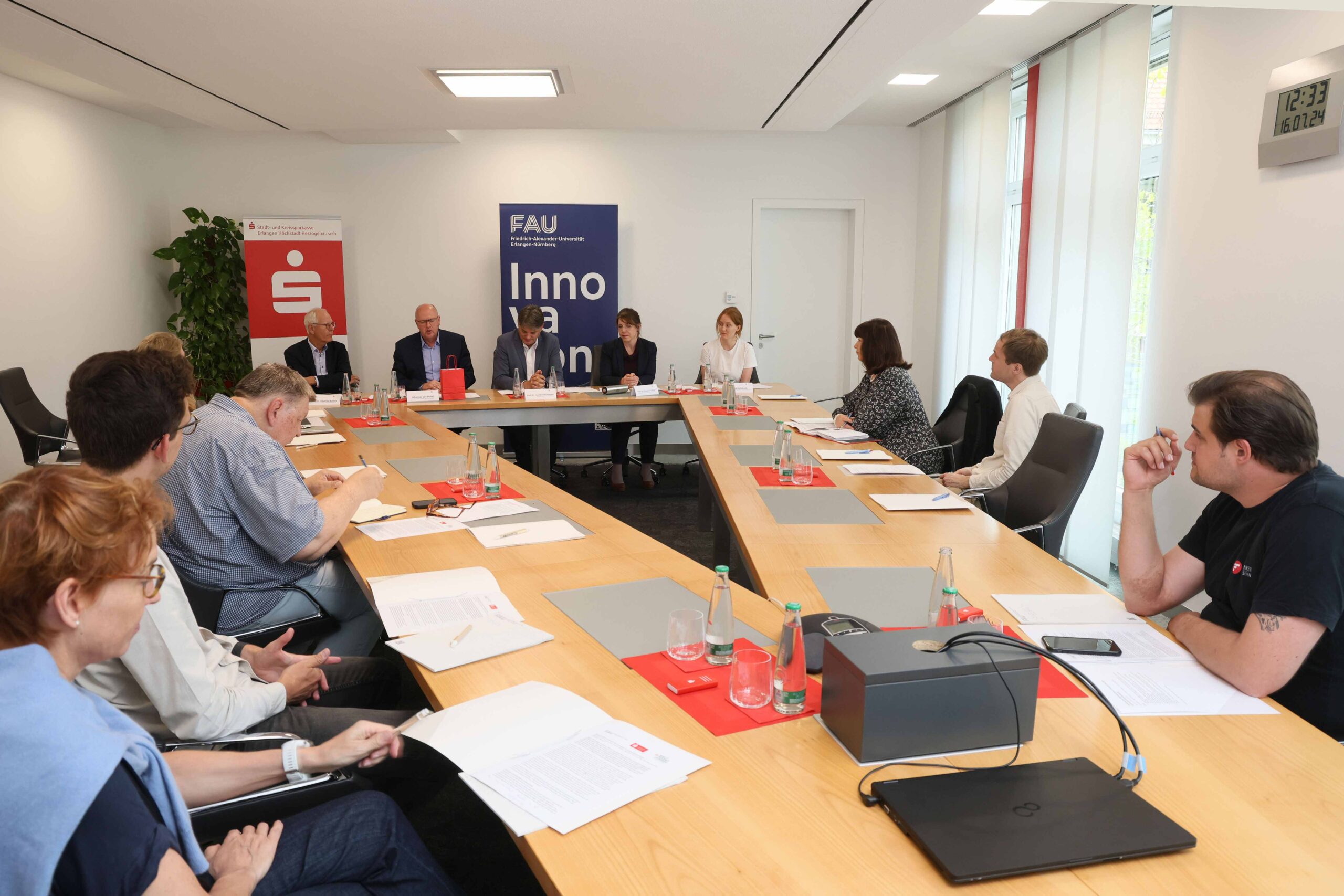 Auf dem Bild sind Vertreterinnen und Vertreter der Initiatoren FAU, Unibund und Sparkasse zu sehen, welche um einen Tisch versammelt zusammen mit der Presse in einem Pressegespräch den mittlerweile fünften Weltmarktführer Innovation Day am 18.9. vorstellen