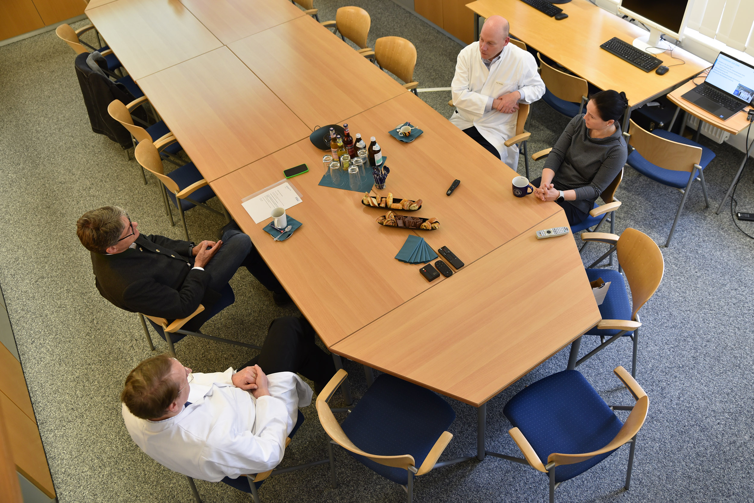 Drei Männer und eine Frau sitzen an einem Tisch.