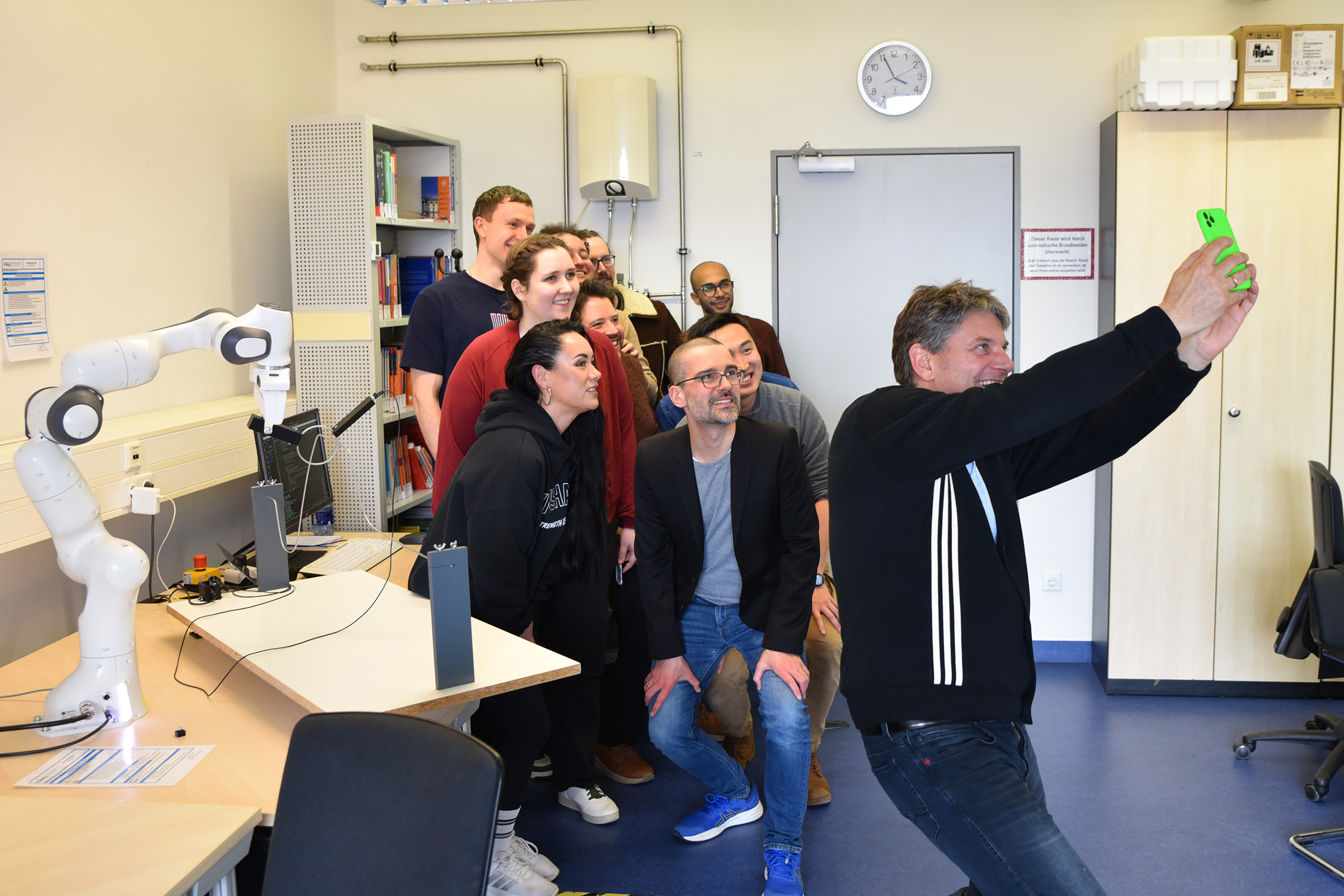 FAU-Präsident Hornegger fotografiert ein Selfie mit Philipp Beckerle und seinem Team.