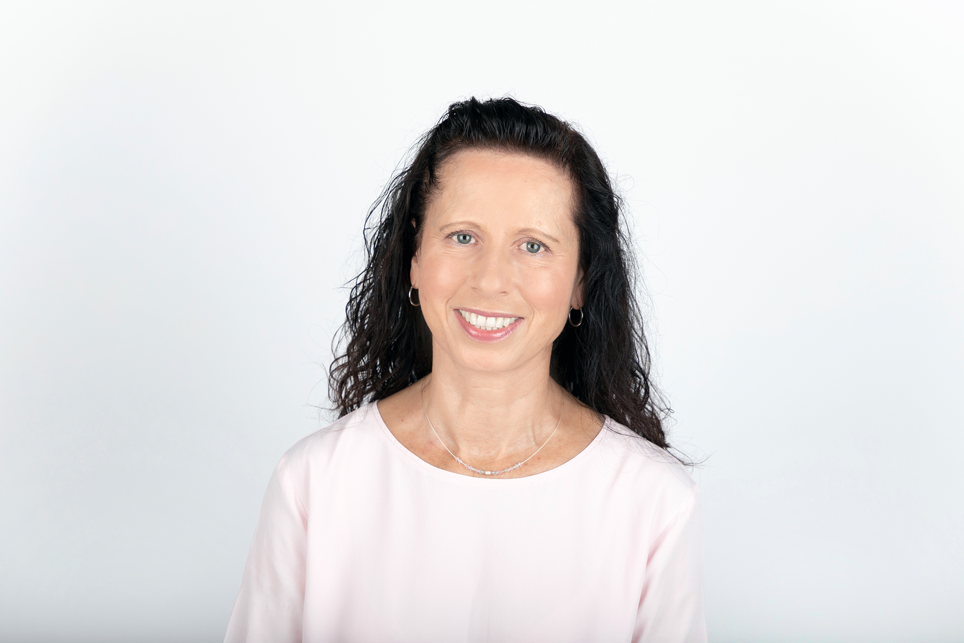 Frau (Dr. Andrea Dakkouri-Baldauf) mit schwarzen langen Haaren vor weißem Hintergrund.