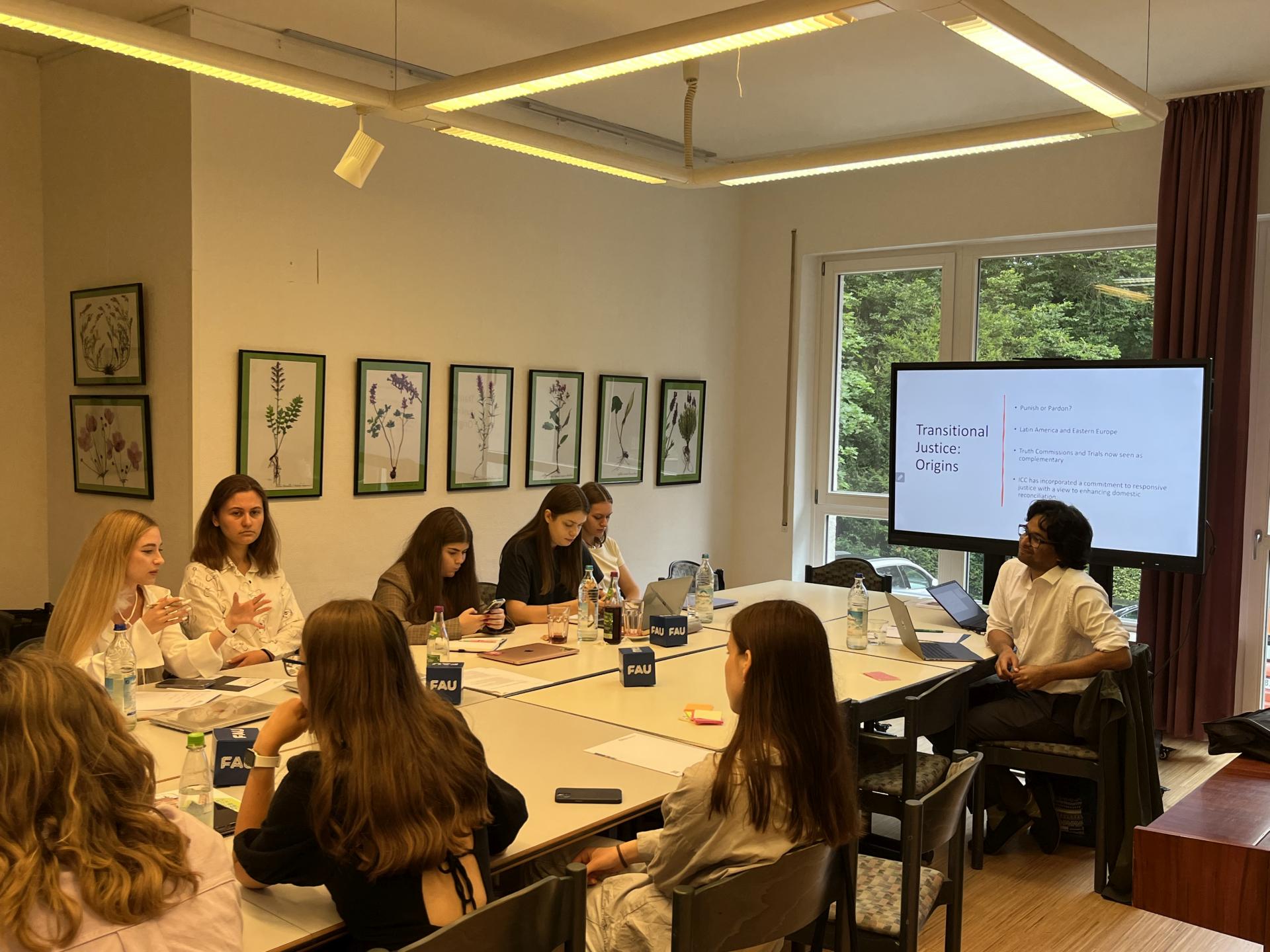 Studierende an einem großen Tisch in einem Seminarraum.