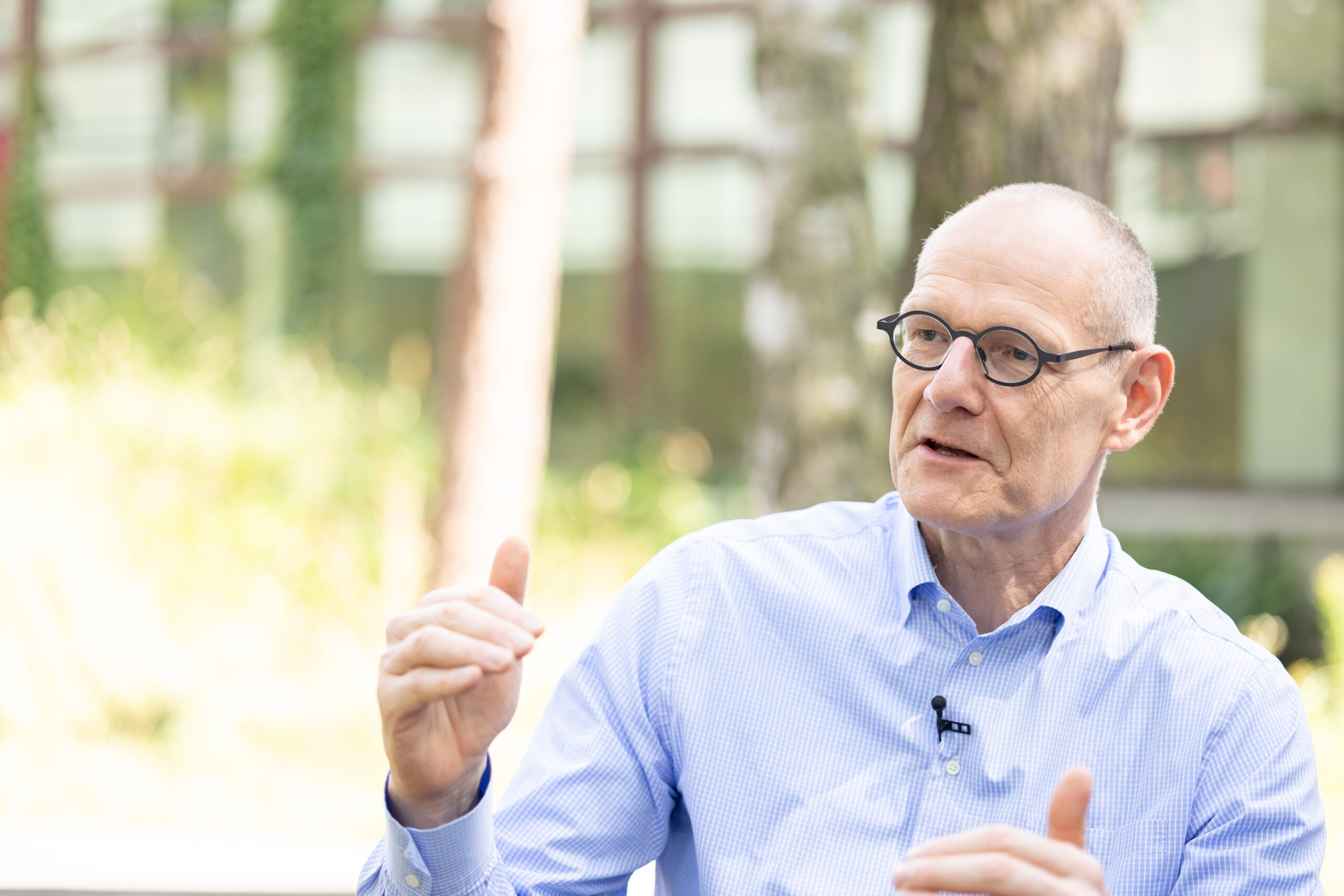 Dr. Bernd Montag an der Naturwissenschaftlichen Fakultät der FAU, auf einem Stuhl sitzend im Grünen vor dem Physikum.