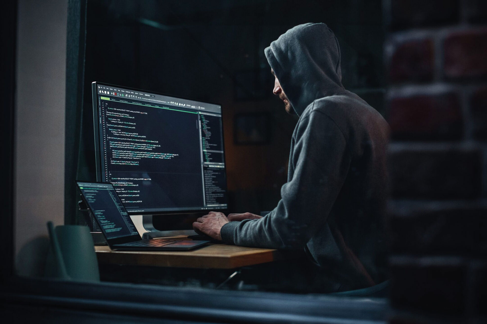 Hacker mit Hoodie am Computer sitzend