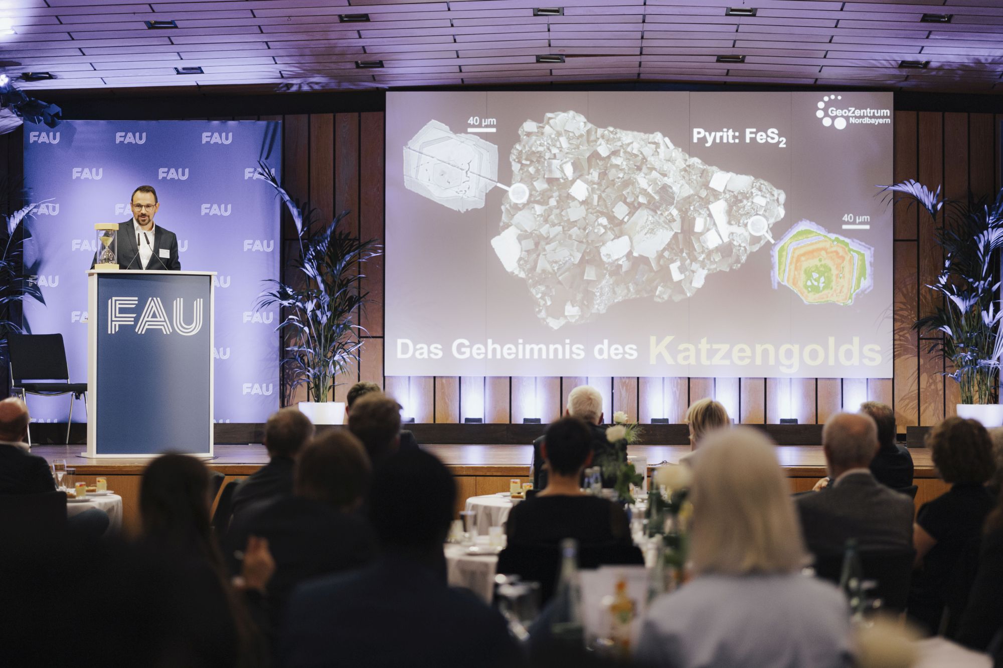 FAU Awards 2024 Menschen an Tischen auf der Bühne Forscher und Präsentation über das Geheimnis des Katzengolds