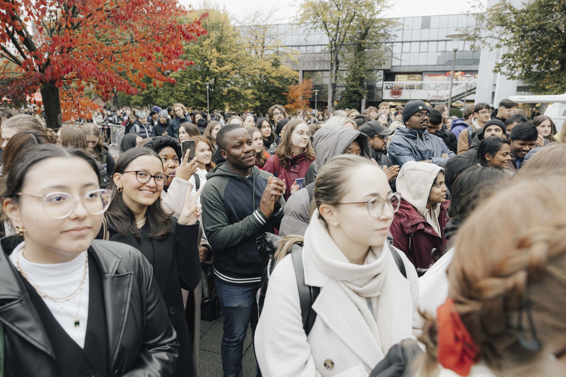 Menschen draußen vor der Halle vor der Bühne. Sie applaudieren.