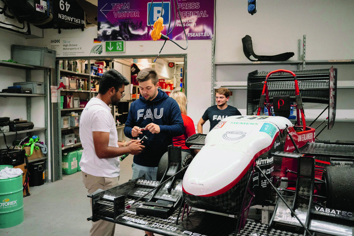Mehrere Studierende arbeiten an einem Rennwagen in der Werkstatt.