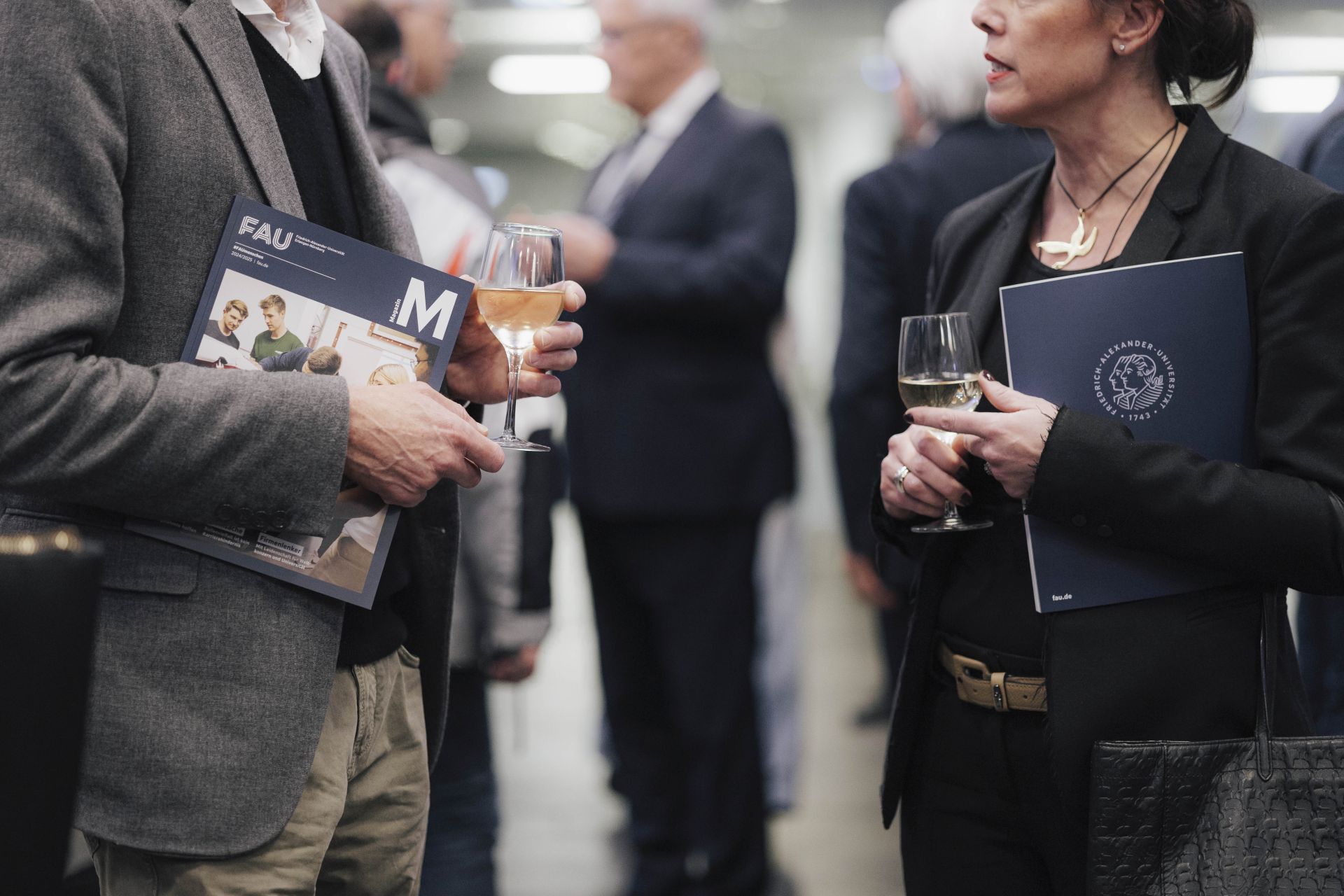 Zwei Personen unterhalten sich, eine hält das FAU Magazin in der Hand.