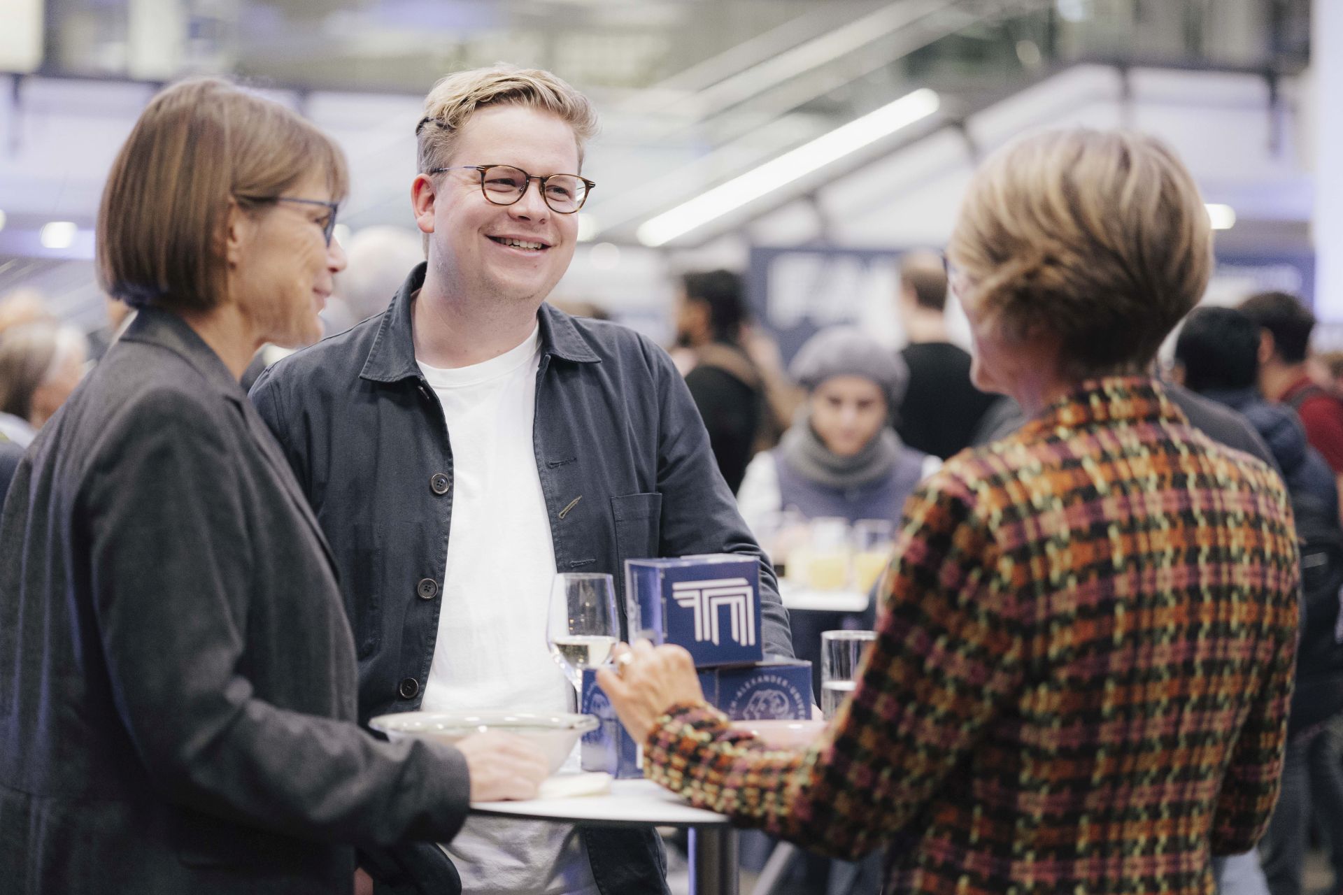 Drei Personen unterhalten sich beim Dies academicus an einem Stehtisch.