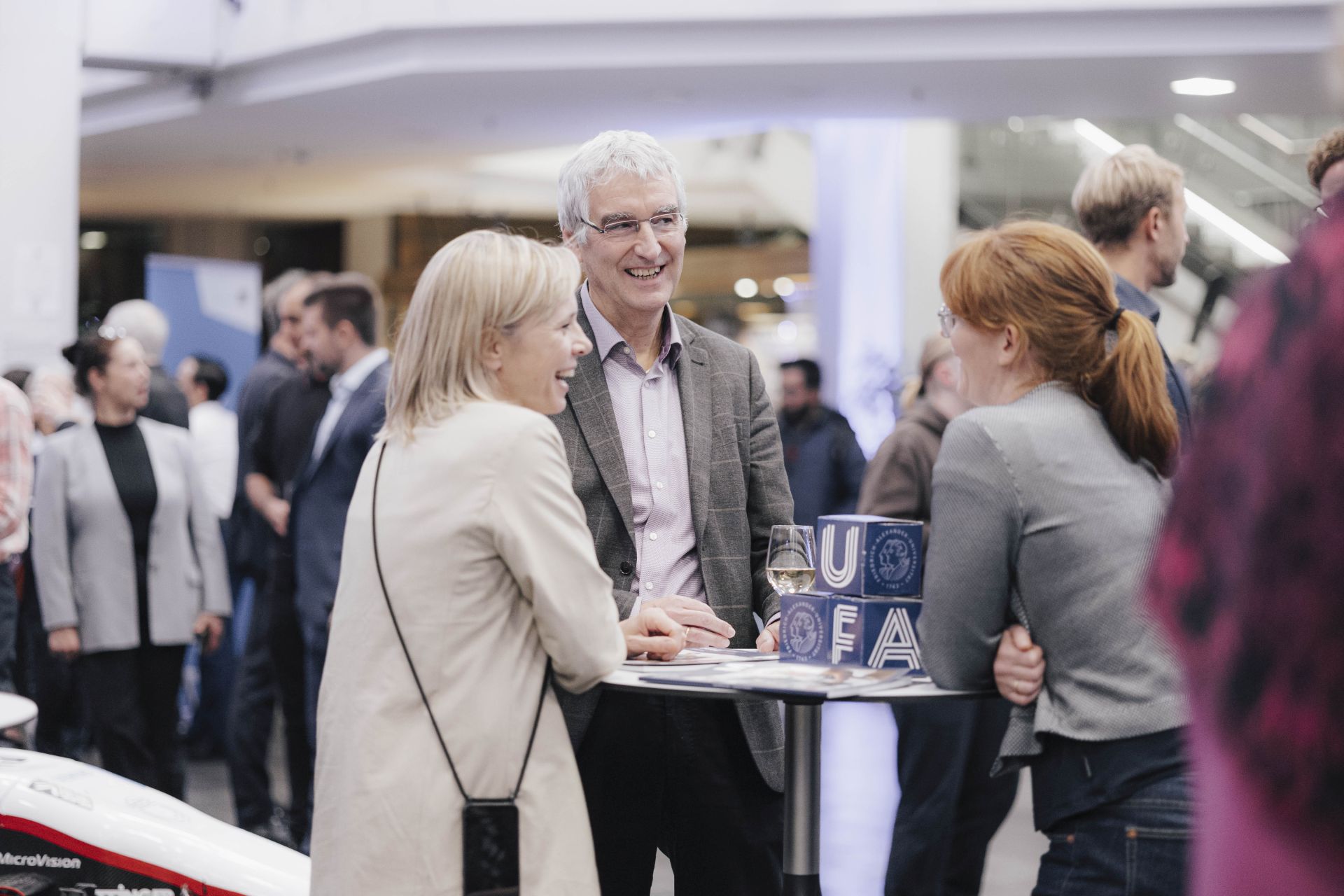 Drei Personen unterhalten sich an einem Stehtisch.