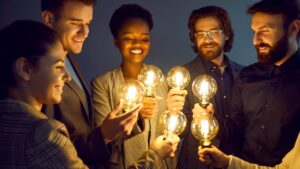 Gruppe von Menschen, die Glühbirnen halten. Symbolbild für Wissenschaftler/-innen mit neuen Ideen