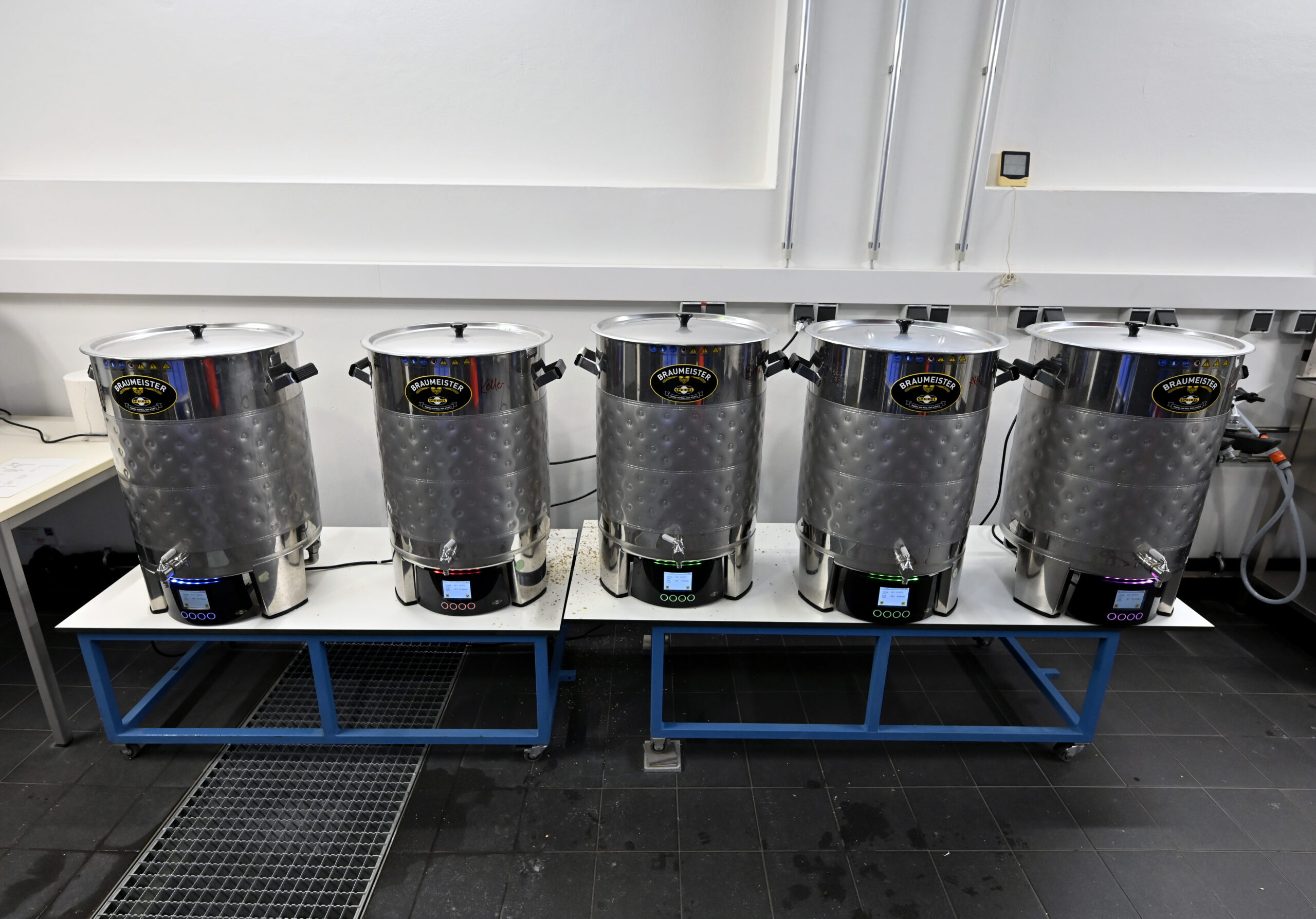 Fünf Metallkessel, die in einer Rehe stehen.