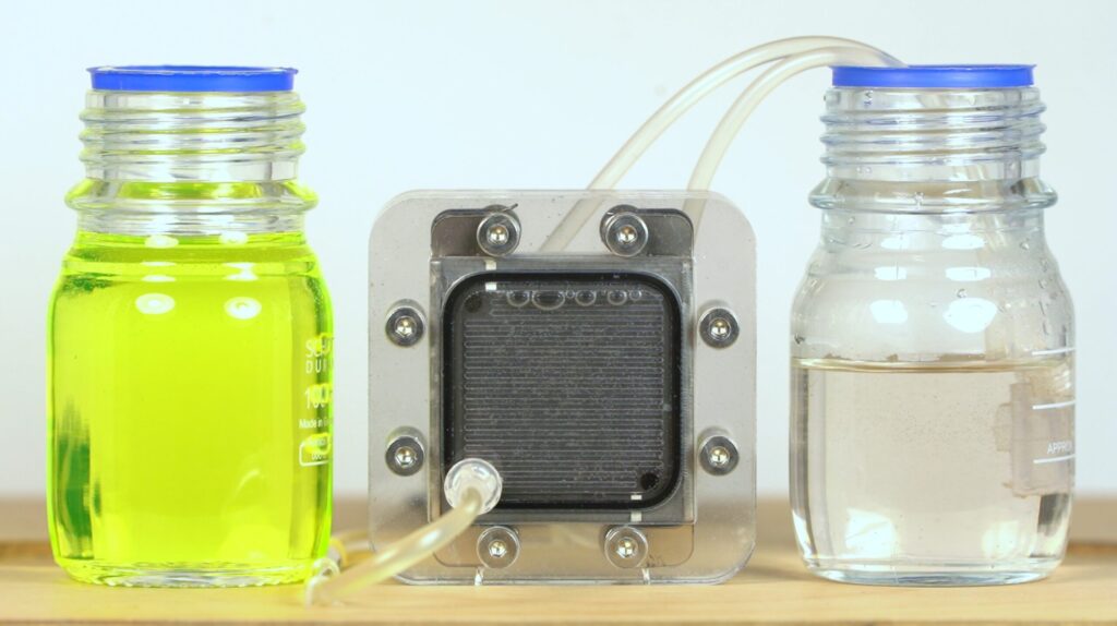 Der Demonstrator von CiX. 2 Gefäße, links mit gefärbetem Wasser, rechts mit klarem Wasser, durch Schläuche mit dem Entfärber verbunden.