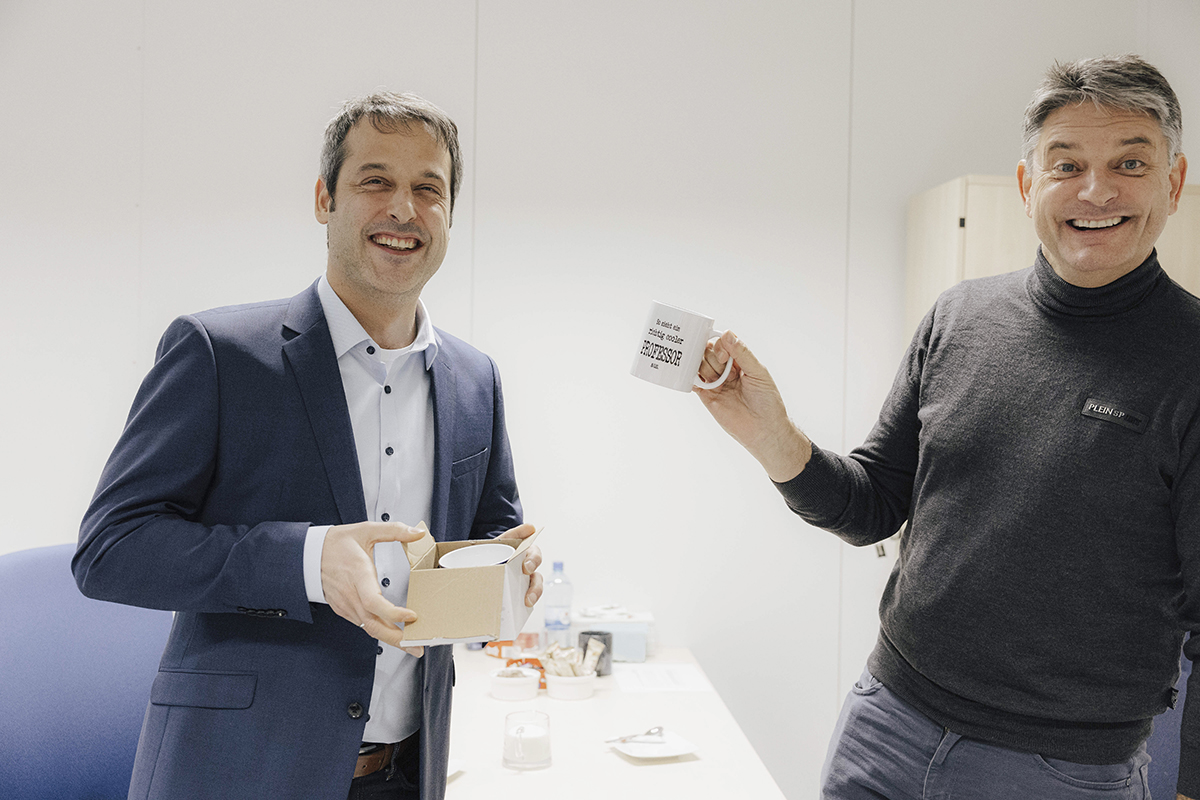 FAU-Präsident Hornegger blödelt mit Rosshart, der gerade ein Geschenk auspackt.