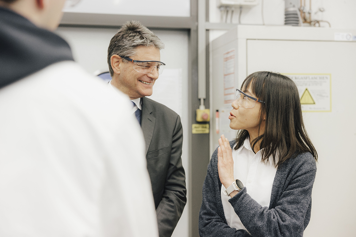 Professor Ng, eine junge Asiatin mit dunklen Haaren erklärt FAU Präsident etwas. 