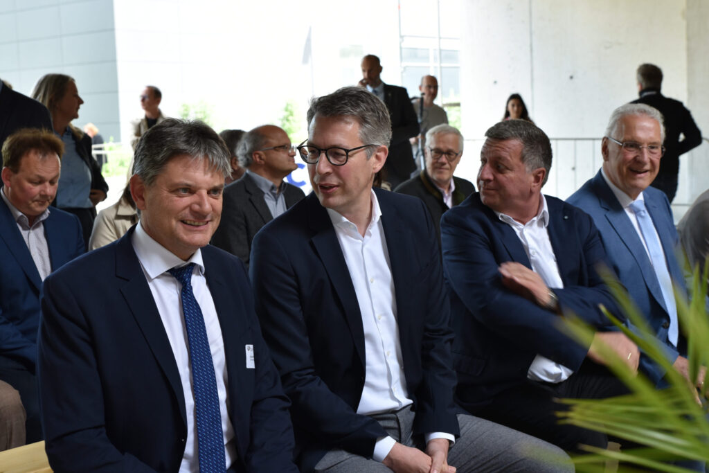 4 Männer in Anzügen sitzen auf einer Bank.