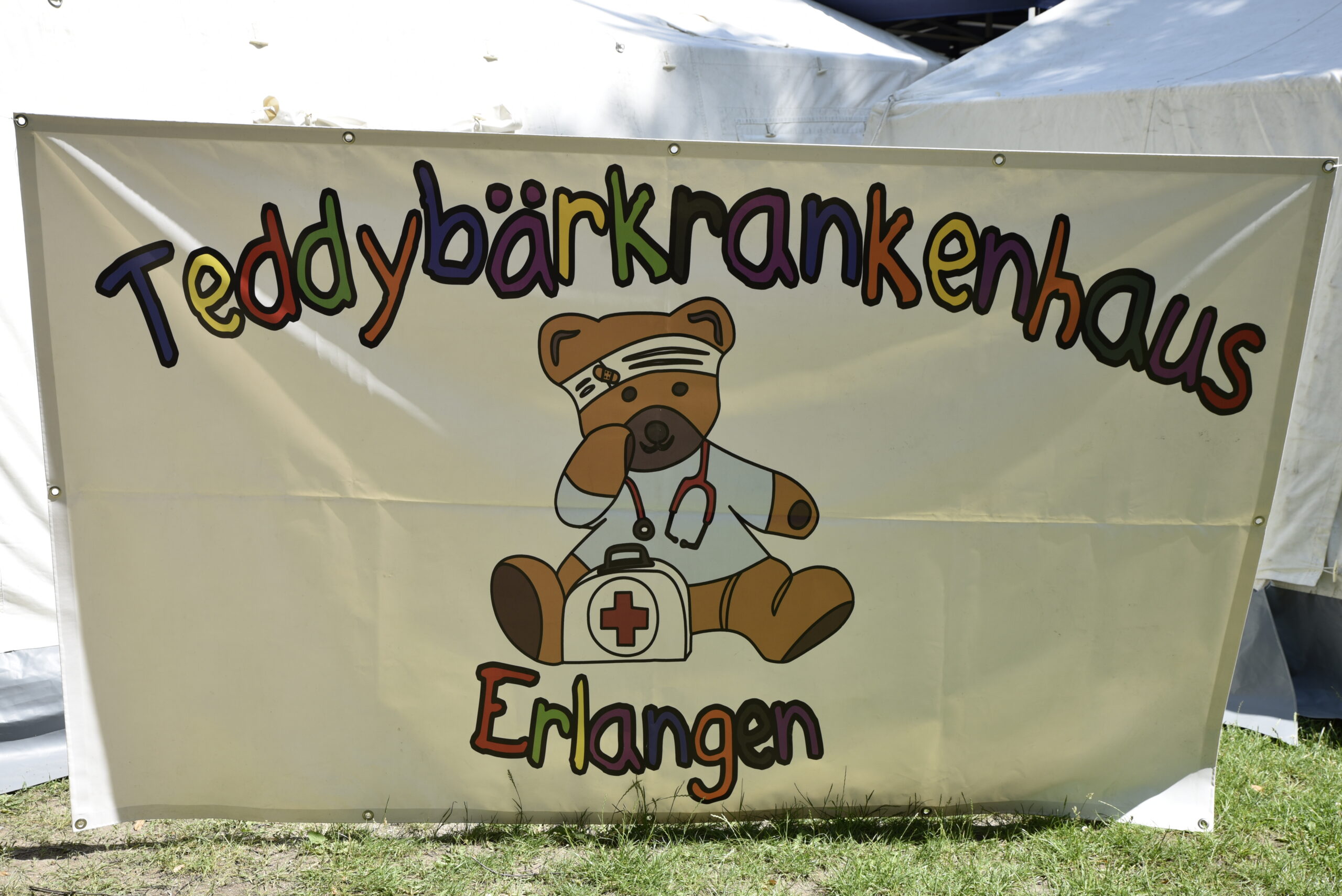 Banner mit Logo der des Teddybärenkrankenhaus,. Ein teddybär mit Verband und Arztkoffer.