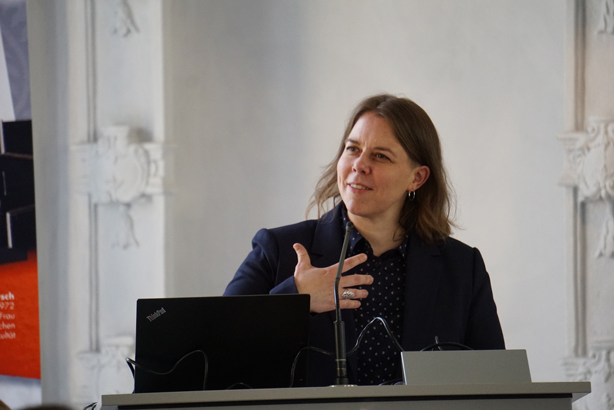 Häneke, eine jüngere frau mit schulterlangen Haaren, bei ihrer Rede an einem Stehpult.