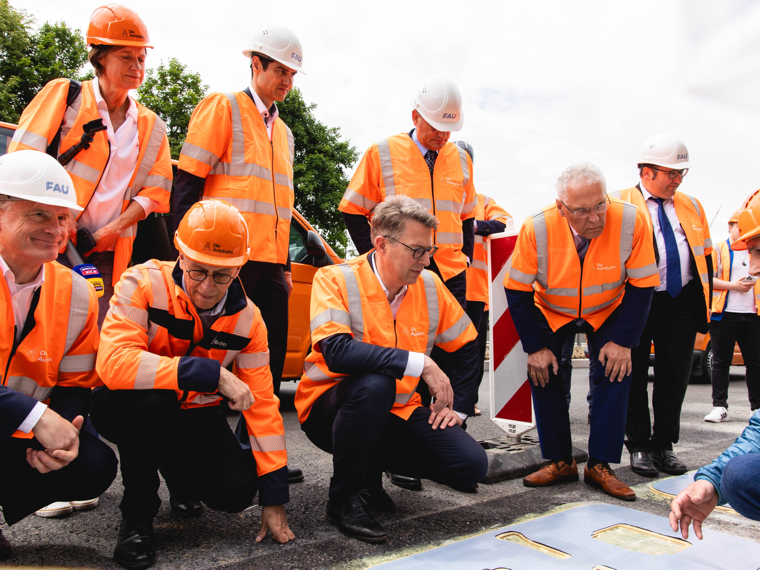 Eine Gruppe Menschen kniet auf Asphalt um sich eine Induktionsspule anzuschauen