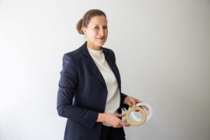 Prof. Völkel, eine Frau mit zurückgebundenen Haaren hält zwei Zahnräder in der Hand.