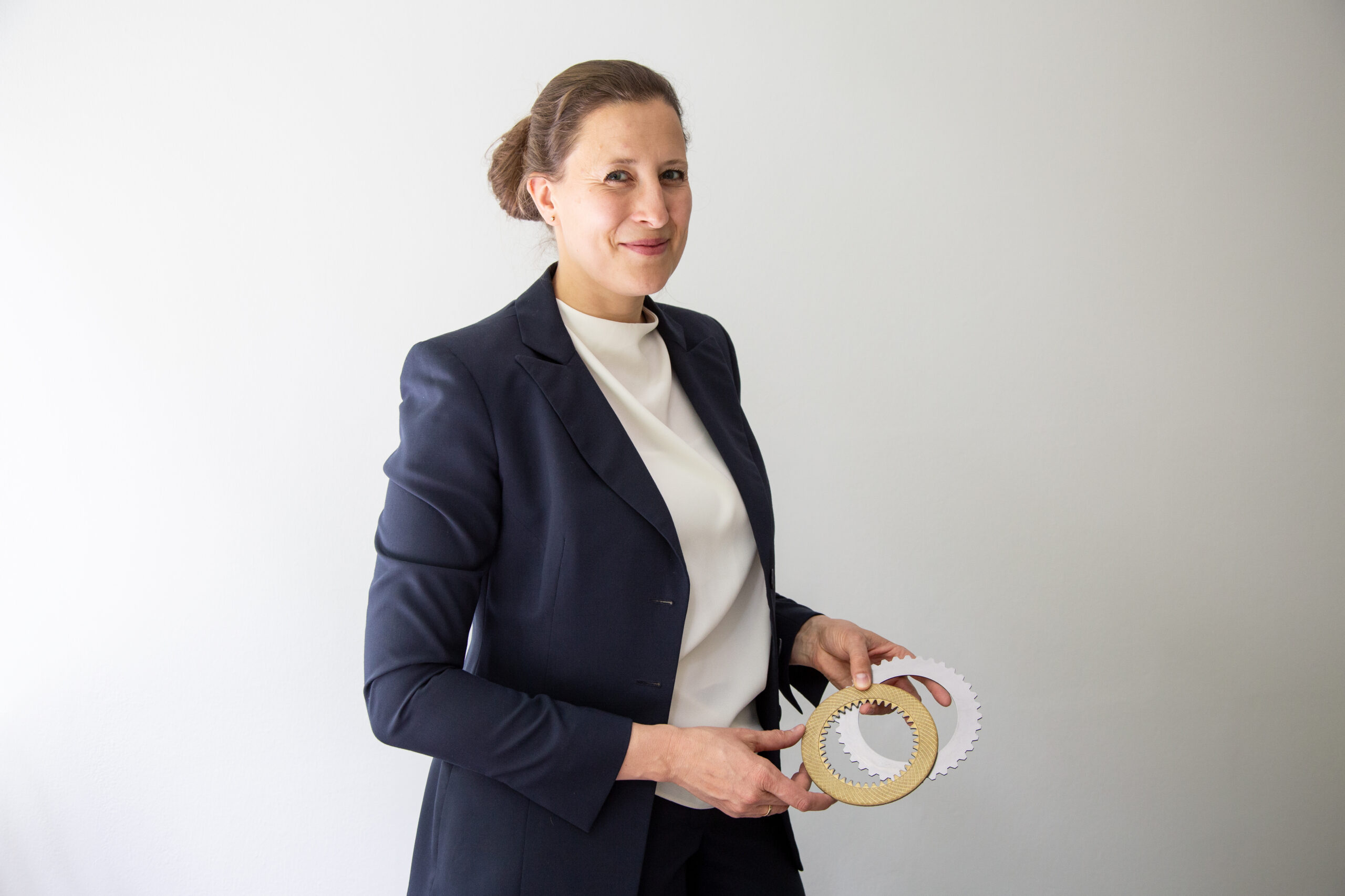 Prof. Völkel, eine Frau mit zurückgebundenen Haaren hält zwei Zahnräder in der Hand.