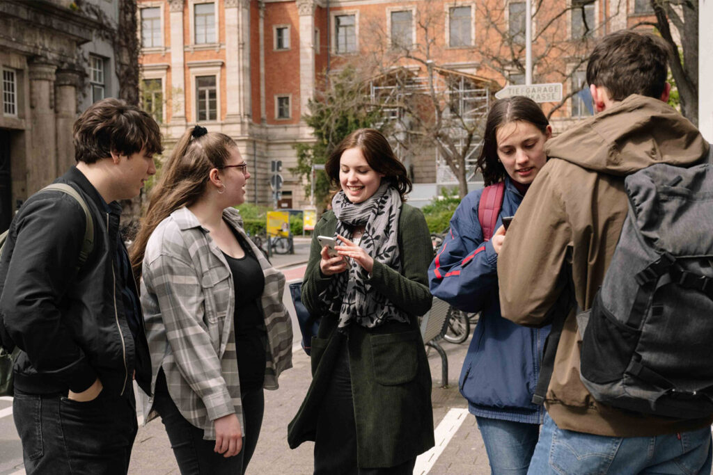 Fünf Studierende stehen vor der Universitätsbibliothek.